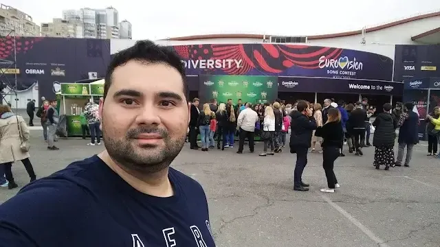 Andrés frente a la Arena de Lisboa 2018, con bandera de El Salvador y camiseta de EUVIN 87 — Fundador de EUVIN 87 en Eurovisión